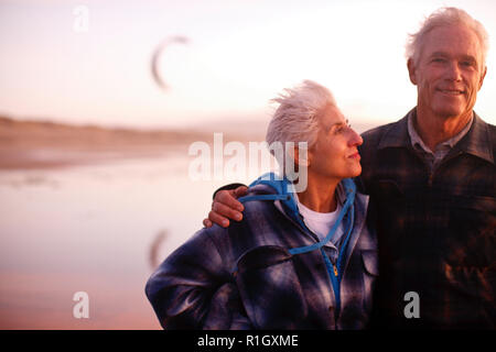 Senior couple standing on beach together Stock Photo