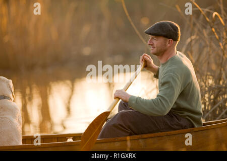 Man sitting in a canoe with his dog. Stock Photo