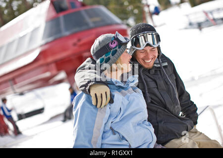 Couple sitting together in their snow gear Stock Photo