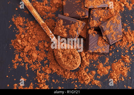 Broken dark chocolate with cocoa powder. Close up. Stock Photo