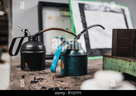 Two old metal container containing ball bearing grease placed on wooden table with engineering drawing in the background Stock Photo