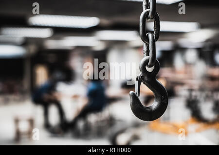 Rusted chain hook used to hold metal in workshop room with blurred background Stock Photo