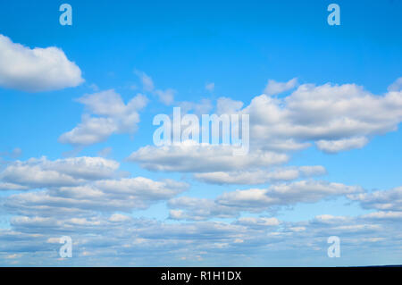 Wavy, porous curly clouds on the blue sky. Nature background. Stock Photo