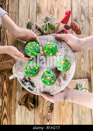 Women's and children's hands are holding Christmas muffins in the form of green Christmas trees Stock Photo