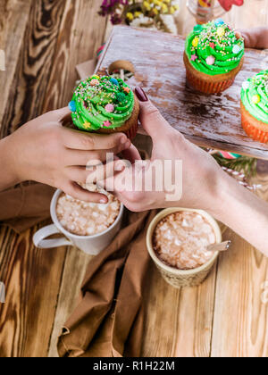 Women's and children's hands are holding Christmas muffins in the form of green Christmas trees Stock Photo