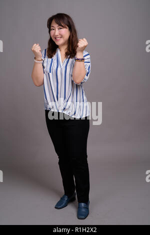 Full length portrait of Japanese businesswoman against gray background Stock Photo