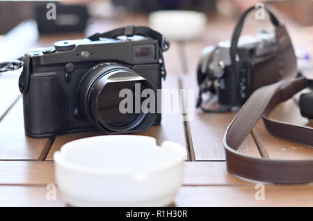 Mirrorless cameras during the break between filming and a white ashtray lying on a wooden table Stock Photo