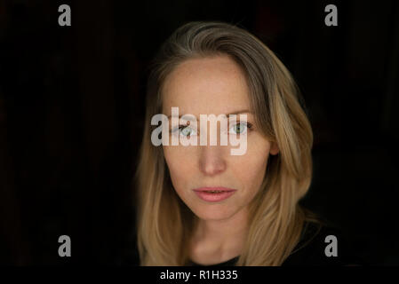 Close-up of woman with braces and blond hair, green eyes. Horizontal headshot with black background and copy space. MR available on request. Mar 2018 Stock Photo