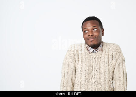 doubtful african man in sweater shrugs shoulders with confusion Stock Photo