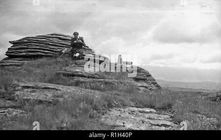 1950s, historical, a lady walker sitting on a rocky peak, a tor or craig, in the snowdonia national park, Wales, Stock Photo