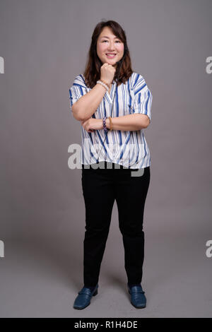 Full length portrait of Japanese businesswoman against gray background Stock Photo