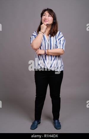 Full length portrait of Japanese businesswoman against gray background Stock Photo