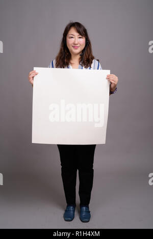 Full length portrait of Japanese businesswoman holding white board Stock Photo