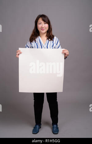 Japanese businesswoman holding white board with copyspace Stock Photo