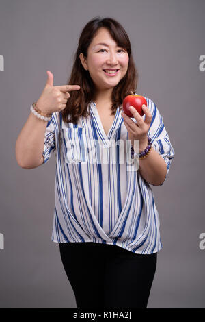 Mature beautiful Asian businesswoman holding apple fruit Stock Photo