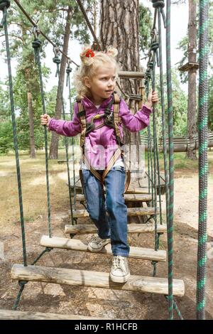 Girl 4, 5 years old in adventure climbing high wire park, active lifestyle of children. Stock Photo