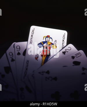 Playing cards showing a Joker against a dark background. Stock Photo