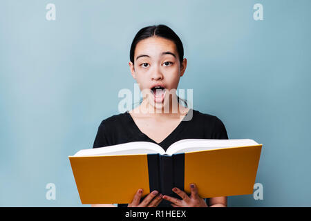 Young female teenager is excited about reading a book Stock Photo