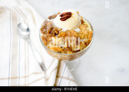 Pecan Cobbler with Vanilla Ice Cream: A dish of southern pecan cobbler in a glass dessert bowl with a spoon Stock Photo