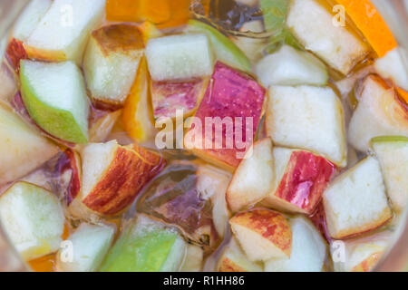 Detailed view at the sliced fruits, apple, orange and cucumber, on champagne sangria drink... Stock Photo