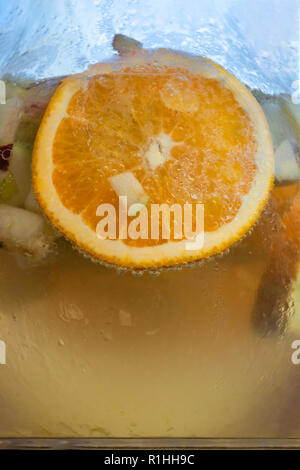 Detailed view at the jar with sliced orange, apple, and cucumber, on champagne sangria drink... Stock Photo