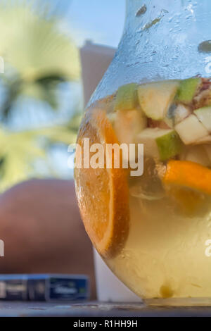 Detailed view at the jar with sliced orange, apple, and cucumber, on champagne sangria drink... Stock Photo