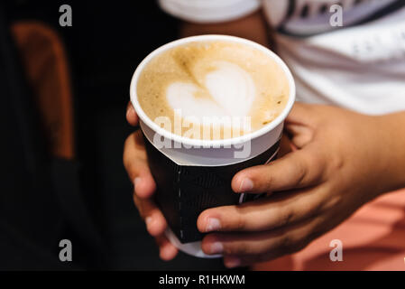 Young male hands holding a cup of coffee drink, heart pattern in a coffee cup, top view Stock Photo