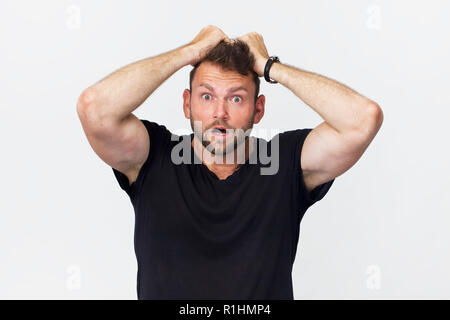 Young hipster man with surprised expression on face. Portrait against white wall Stock Photo