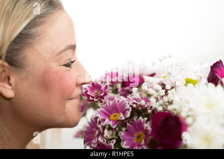 Beautiful woman being happy and smelling flowers she just received on an isolated white background Stock Photo