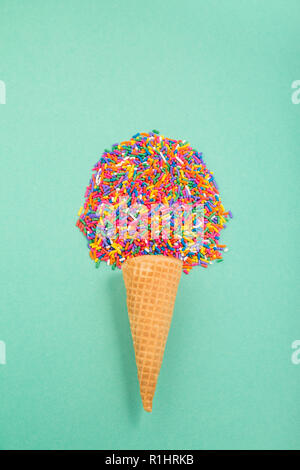 Ice cream cone with sprinkles in the shape of a scoop on a pale green background Stock Photo