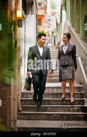 Business colleagues having a discussion while walking side by side down some steps in an urban city. Stock Photo