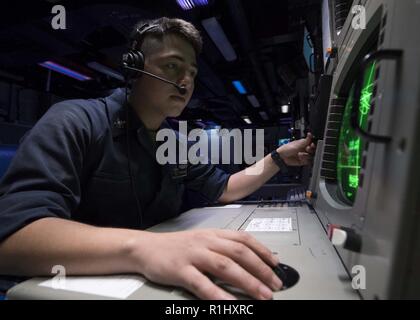 SOUTH CHINA SEA (Sept. 21, 2018) Sonar Technician 2nd Class Alberto Folch, from Hollywood, Fla., looks at a monitor in the combat information center of the Ticonderoga-class guided-missile cruiser USS Antietam (CG 54) during exercise Valiant Shield. Valiant Shield is a U.S. only, biennial field training exercise (FTX) with a focus on integration of joint training in a blue-water environment among U.S. forces. This training enables real-world proficiency in sustaining joint forces through detecting, locating, tracking, and engaging units at sea, in the air, on land, and in cyberspace in respons Stock Photo