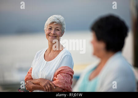 Happy mature woman enjoys the sea air with her friend on a walk together. Stock Photo