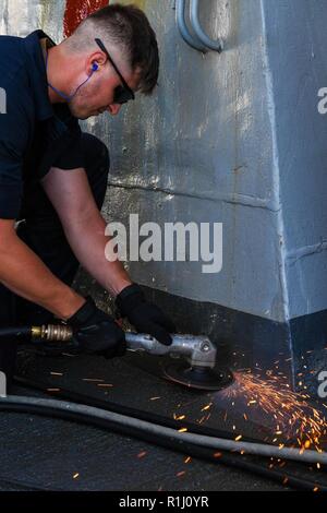 ATLANTIC OCEAN (Sept. 24, 2018) Seaman Apprentice Jackson Perkins performs deck maintenance aboard the Arleigh Burke-class guided missile destroyer USS Mitscher (DDG 57). Mitscher is on a regularly scheduled deployment in support of maritime security operations and theater security cooperation efforts. Stock Photo