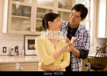 Adult son standing in a kitchen with his mother discussing her medication. Stock Photo
