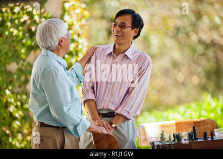 Smiling mid adult man sharing a joke with his father. Stock Photo