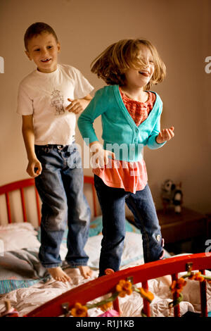 Brother and sister bouncing on a bed. Stock Photo