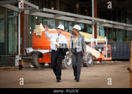 Two smiling engineers discussing plans on a construction site. Stock Photo