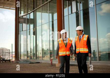 Two smiling engineers discussing plans on a construction site. Stock Photo
