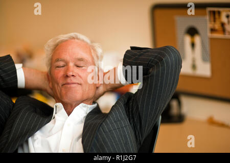 Businessman takes a break from work leaning back on his chair with eyes closed. Stock Photo