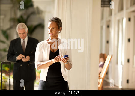Two business colleagues walking while using cell phone. Stock Photo