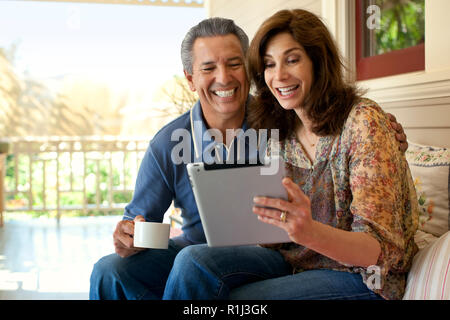 Couple looking at an ipad on their verandah. Stock Photo