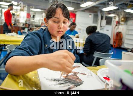 ATLANTIC OCEAN (Sept. 21, 2018) Aviation Ordnanceman 3rd Class Raquel Worley, from San Benito, Texas, paints a picture during a Morale, Welfare and Recreation sponsored paint night aboard the aircraft carrier USS George H.W. Bush (CVN 77). GHWB is underway in the Atlantic Ocean conducting routine training exercises to maintain carrier readiness. Stock Photo