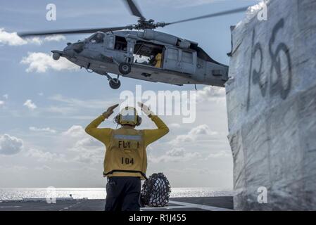 ATLANTIC OCEAN (Sept. 22, 2018) Aviation Boatswain's Mate (Handling) 3rd Class Andrew Harvey, from Franklinton, Louisiana, directs an MH-60S Sea Hawk, attached to Helicopter Sea Combat Squadron (HSC) 9, during a vertical replenishment aboard the aircraft carrier USS George H.W. Bush (CVN 77). GHWB is underway in the Atlantic Ocean conducting routine training exercises to maintain carrier readiness. Stock Photo