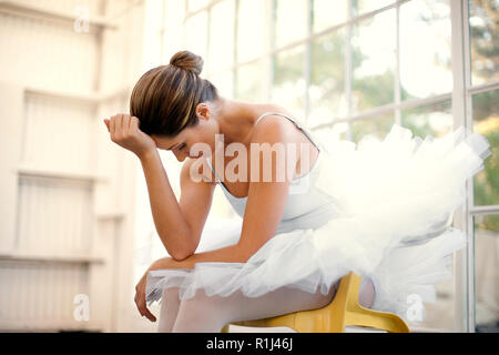 Mid adult ballerina sitting with her head in her hands. Stock Photo