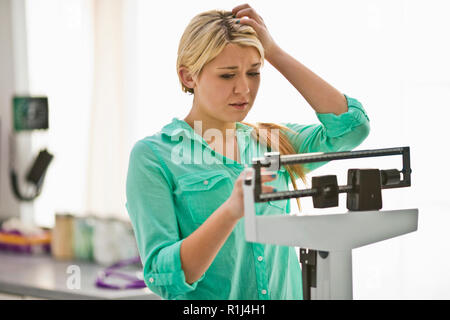 https://l450v.alamy.com/450v/r1j4h1/unhappy-young-woman-looking-at-her-weight-on-a-medical-weight-scale-inside-a-doctors-office-r1j4h1.jpg