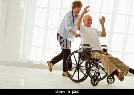 Smiling mature doctor pushing an elderly patient in a wheelchair. Stock Photo