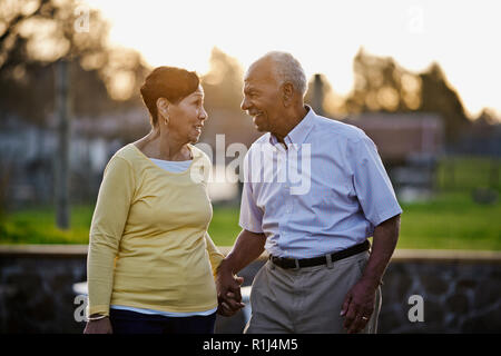 Happy senior couple holding hands while walking in the back yard together. Stock Photo
