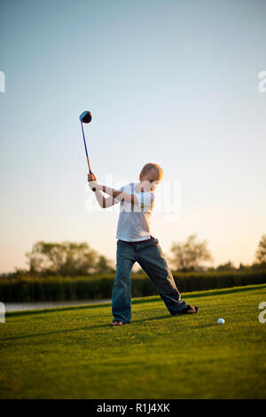 Young boy swinging a gold club on a gold course. Stock Photo