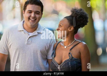 Happy young couple walking side by side down an urban street. Stock Photo